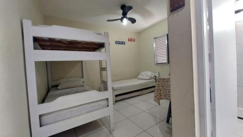two bunk beds in a room with a ceiling fan at Kit Ocian in Praia Grande