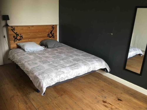 een bed in een slaapkamer met een spiegel en houten vloeren bij Maison au calme proche des cures in Jonzac