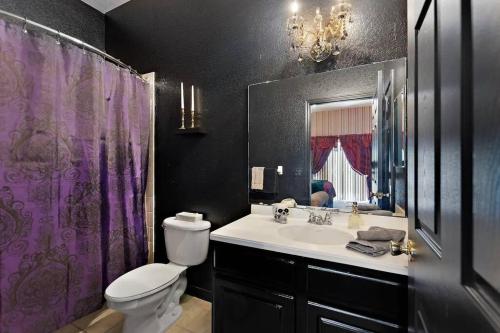 a bathroom with a sink and a toilet and a purple shower curtain at A Spooktacular Haunted Mansion. in Kissimmee