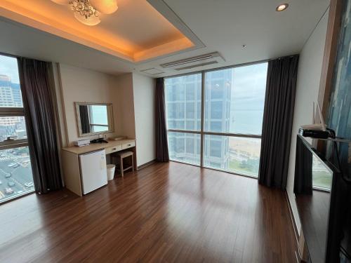 an empty room with a desk and large windows at Elysia Boutique Hotel in Busan