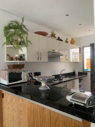 a kitchen with a black counter top with a microwave at Beralmar Asilah Chez FATIMA in Asilah