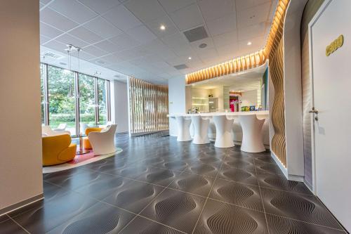 an office lobby with white tables and yellow chairs at prizeotel Antwerp-City in Antwerp