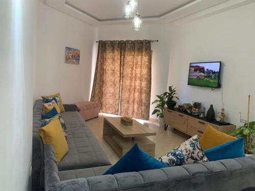 a living room with a couch and a tv at Beralmar Asilah Chez FATIMA in Asilah