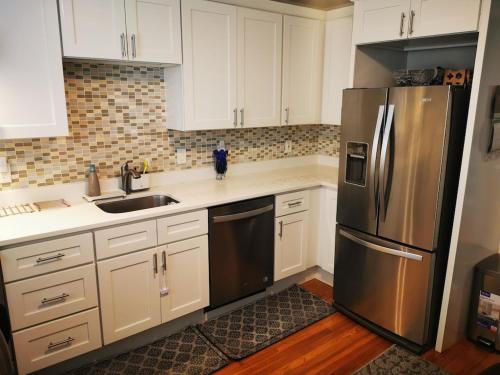 cocina con armarios blancos y nevera de acero inoxidable en Location+Comfort+Convenience en Boston