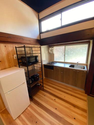 eine kleine Küche mit einem Kühlschrank und einem Fenster in der Unterkunft guesthouse碧 in Okinoshima