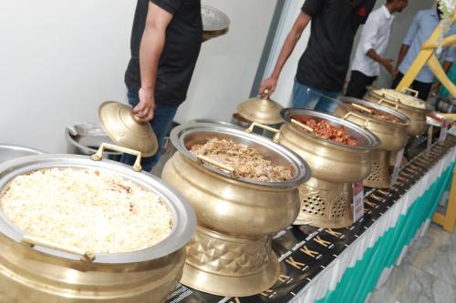 a row of metal bowls of food on a table at HYDEPARK REGENCY in Palakkad