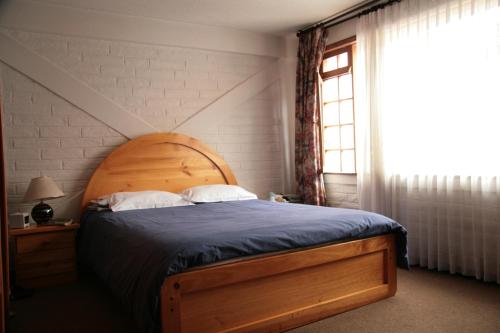 a bedroom with a bed with a wooden headboard and a window at Apartamentos Los Quipus in Quito