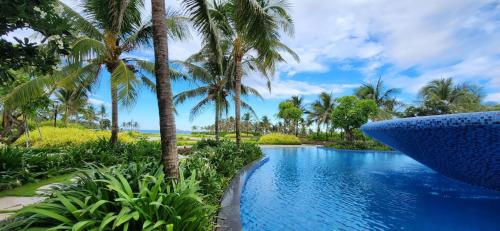 a pool at the resort with palm trees at Wyndham Grand KN Paradise Cam Ranh in Cam Ranh