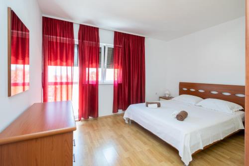 a bedroom with a white bed and red curtains at Apartments with a parking space Sali, Dugi otok - 16324 in Sali