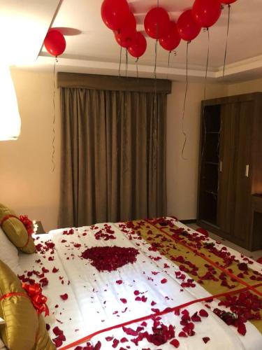 ein Bett mit roten Ballons und roten Blumen darauf. in der Unterkunft منازل الساهر للوحدات المخدومة فرع 2 in Al Qunfudhah