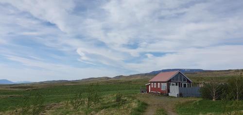 una pequeña casa roja y blanca en un campo en Árfell, en Varmahlid