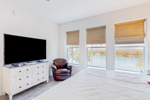 a white bedroom with a television and a chair at Five O'Clock Somewhere in Bradenton