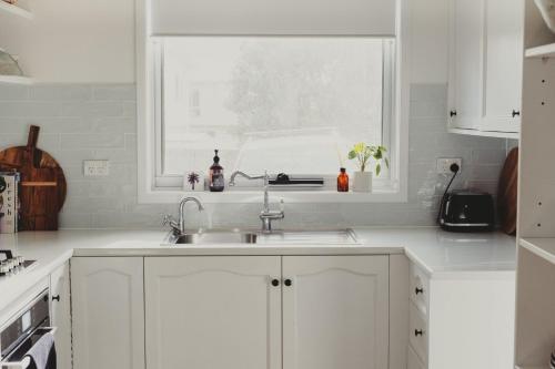 a kitchen with white cabinets and a sink and a window at Reardon Retreat in Port Fairy