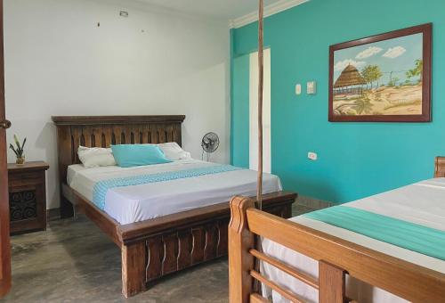 1 dormitorio con 2 camas y pared azul en Coccoloba Beach Hostel, en Dibulla
