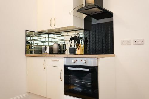 cocina con armarios blancos y horno en S.H Apartments en Glasgow