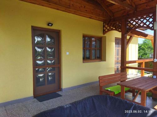 a porch with a wooden door and a table and bench at Holiday home in Kisnana - Ostungarn 44896 in Kisnána