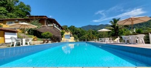 una piscina en un hotel con sillas y sombrillas en Pousada La Dolce Vita Paraty, en Paraty