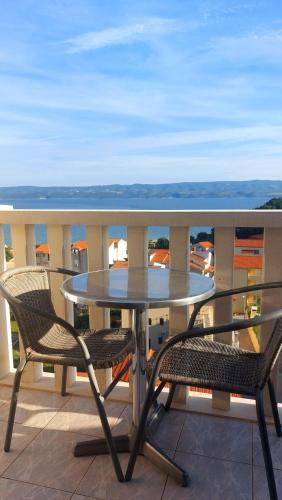 a glass table and two chairs on a balcony at Apartments Duce (122) in Duće