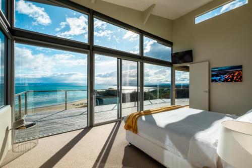 a bedroom with a large window view of the ocean at Halcyon ~ Immerse yourself in the sky and sea in Coles Bay