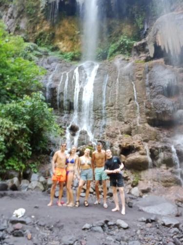 a group of people standing in front of a waterfall at Ijen Farmer Homestay in Banyuwangi