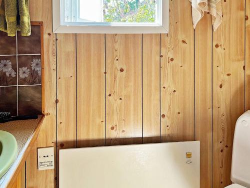 Holiday home NYNÄSHAMN في نينس هامن: حمام بجدران خشبية ومغسلة وثلاجة