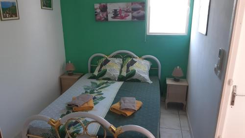 a bedroom with a bed with a green wall at Bungalow Les Iguanes - CocoCyrna in Sainte-Anne