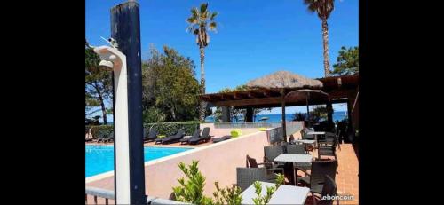 un complexe avec une piscine, une table et des chaises dans l'établissement Appartement Les Marines de Moriani, à San-Nicolao