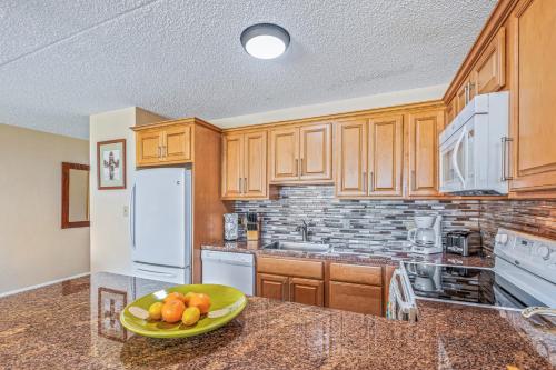 a kitchen with wooden cabinets and a plate of fruit on a counter at Beautiful Condo at Kihei Ali'i Kai, Close to Beach in Kihei