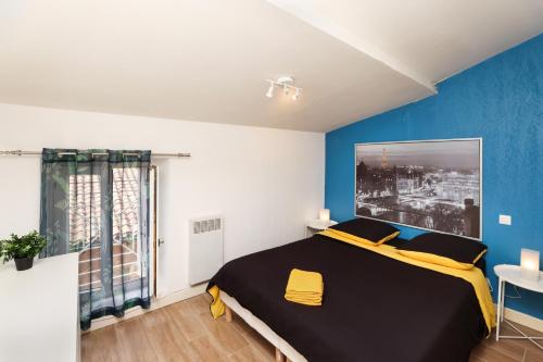 une chambre avec un lit noir et jaune et des murs bleus dans l'établissement City in' BLUE : 1 à 4 personnes, à Carcassonne