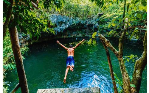 a man jumping into a river in the jungle at Casa Marene in Puerto Morelos