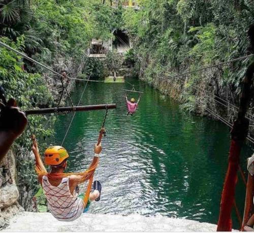 a man hanging on a rope bridge over a river at Casa Marene in Puerto Morelos