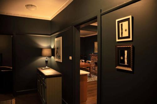 a dark room with a hallway with a table and a lamp at Allawa- Central & Cosy Ballarat Art Deco in Ballarat