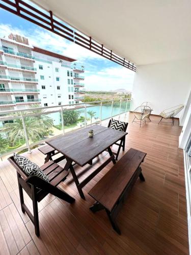 a large balcony with a wooden table and benches at 5010 depa Pacifika de lujo en Marina Mazatlán in Mazatlán