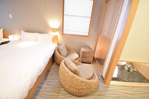 une chambre d'hôtel avec un lit et deux chaises dans l'établissement K-style Higashihonganji, à Shimmachidōri