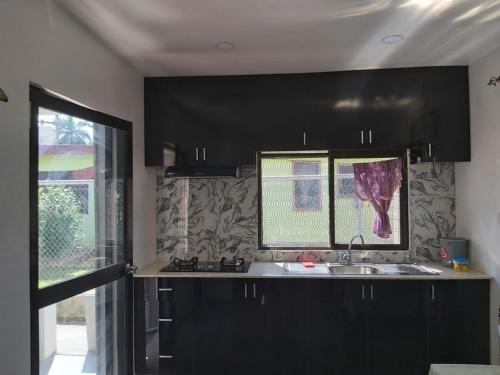 a kitchen with black cabinets and a sink and a window at Island Guesthouse - entire one bedroom unit with kitchen & a bathroom centrally located in Votualevu in Nadi