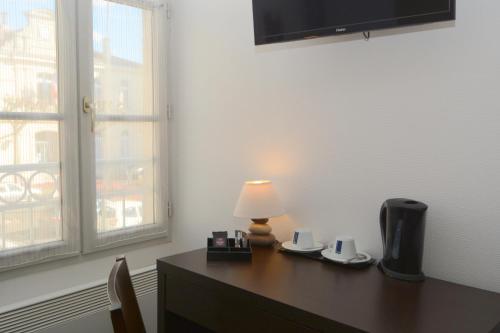 a desk with a lamp sitting on it next to a window at Hôtel Restaurant Le Lion d'Or in Gémozac
