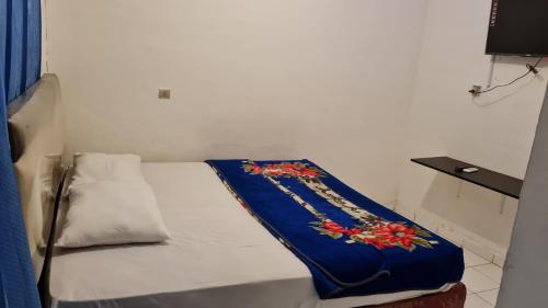 a small bed with a blue blanket on it at Acirasa Homestay Medan in Medan