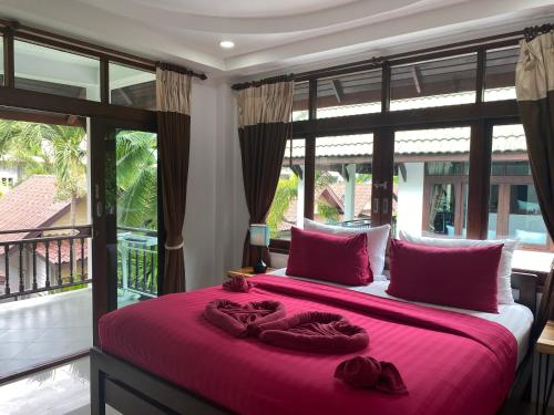 a bedroom with a large bed with red sheets and large windows at Amara Beach Resort Koh Phangan in Haad Yao