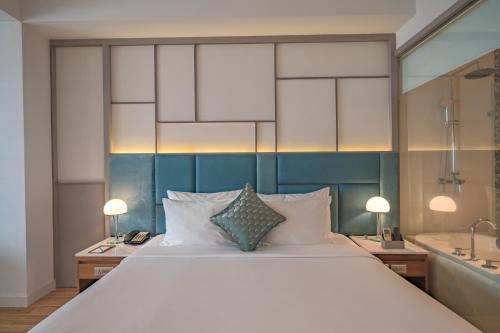 a bedroom with a large white bed and a tub at Seaesta Nha Trang Hotel in Nha Trang