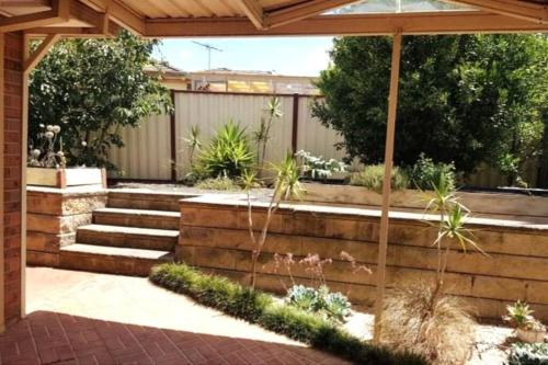 a garden with stairs and a pergola at Roxy - A Spacious Cosy Getaway - Near Mel Airport in Craigieburn