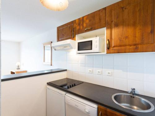 une cuisine avec un évier et un micro-ondes dans l'établissement Appartement 6 pers Peyragudes avec balcon, parking, animaux acceptés - FR-1-695-29, à Germ