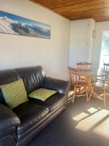 a living room with a leather couch and a table at Pinewood Motels in Fairlie