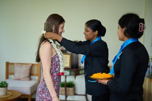 a woman is putting a tie on a girl at Maliekal Heritance Cherai Beach Cochin in Cherai Beach