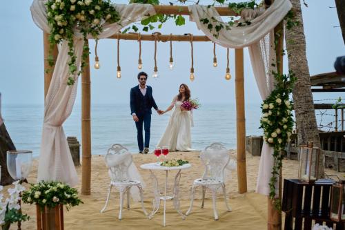 a bride and groom walking down the aisle at their wedding on the beach at Maliekal Heritance Cherai Beach Cochin in Cherai Beach