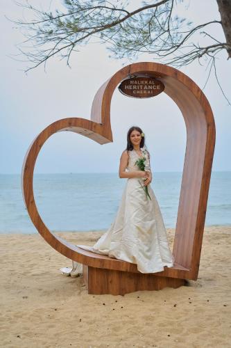 a bride sitting in a wooden arch on the beach at Maliekal Heritance Cherai Beach Cochin in Cherai Beach