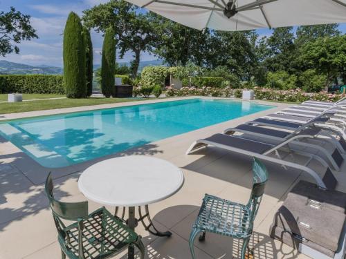 a pool with chairs and a table and an umbrella at Belvilla by OYO Villa Anna in SantʼIppolito