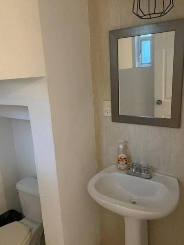 a bathroom with a sink and a mirror and a toilet at Casa Pirules- Parque Metropolitano in León