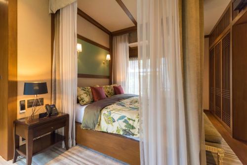 a bedroom with a bed and a table with a lamp at Onsen at Moncham in Mae Rim