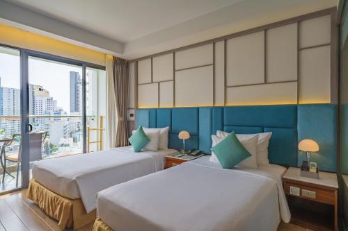 a hotel room with two beds and a balcony at Seaesta Nha Trang Hotel in Nha Trang