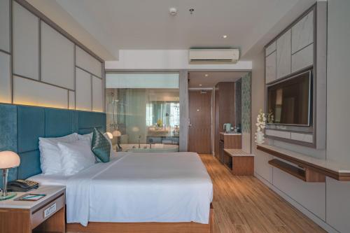 a bedroom with a large white bed and a bathroom at Seaesta Nha Trang Hotel in Nha Trang